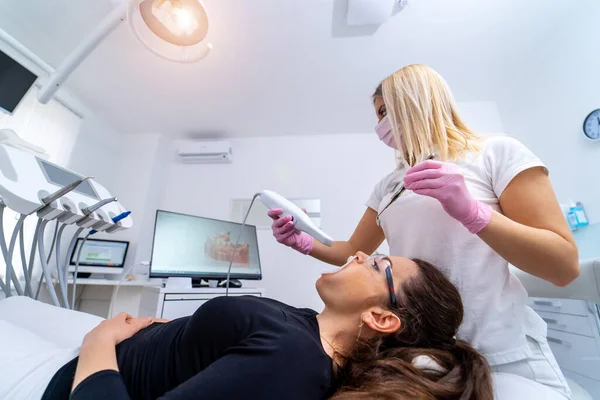 牙医要非常小心地检查和修理戴安全眼镜的年轻女病人的牙齿 — 图库照片
