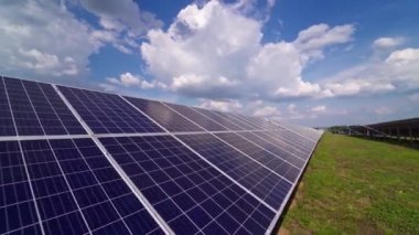 Çimlerin üzerindeki güneş panelleri. Yaz aylarında yenilenebilir yeşil enerji için güneş paneli elektrik santrali. Açık havada uzun sıra mavi paneller..