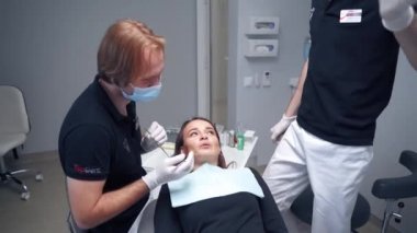Stomatolog kadınların dişlerini tedavi etmeye başlar. Modern klinikte dişçi koltuğunda yatarken kadın hasta ağzını açıyor. Dişçilik.