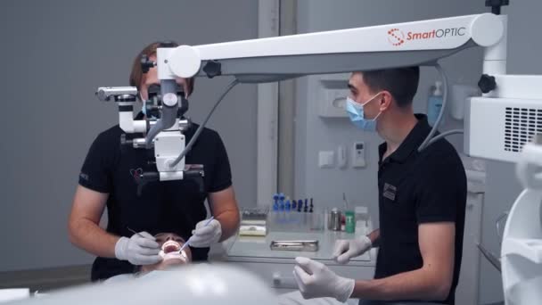 血液学者は近代的な医療機器を使用しています 専門の歯科医が顕微鏡を通して患者の歯を治療します 歯科治療の概念 — ストック動画