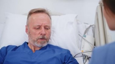 Hastanede bayan ziyaretçisi olan yaşlı bir erkek hasta. Klinikte hasta babasıyla konuşan genç bir kadın. Sağlık hizmetleri. Aile desteği.