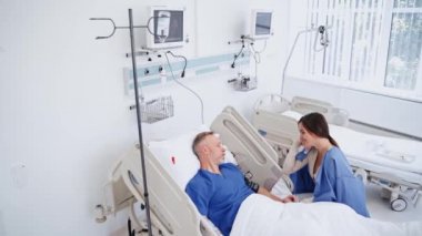 Hasta hastane yatağında yatıyor. Kızı, hasta babasını klinikte ziyaret ediyor. Üst düzey erkek hasta klinikte kadın bir ziyaretçiyle mutlu bir şekilde konuşuyor..