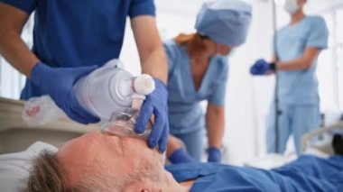 Bilinçsiz bir adama hayat vermek. Doktor hasta bir hastaya acil serviste oksijen maskesi takıyor. Hemşire ve uzman bir hastaya canlandırma yapıyor. Yakın plan..