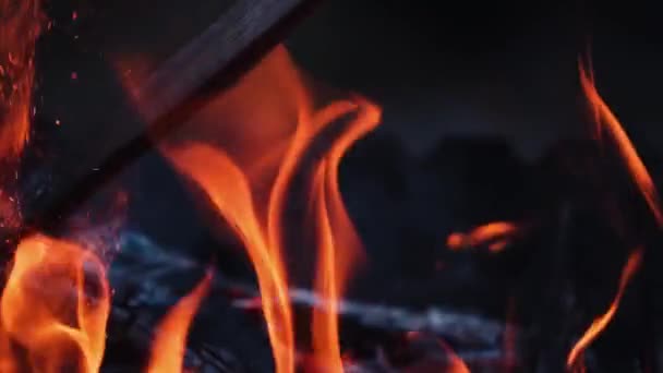 明るい輝きとオレンジの火 木製の棒は明るい炎を作る製錬された丸太を破壊する 暗闇の中で炎の詳細な輝き スローモーション — ストック動画