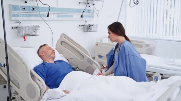 Жінка Відвідує Хворого Батька Старший Чоловік Лежить Медичному Ліжку Розмовляє — стокове відео