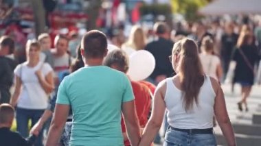 Yaya caddesi insanlarla dolu. Aydınlık bir yaz gününde yolda yürüyen vatandaşlar. Şehir merkezine giderken elinde balon tutan bir kadın..