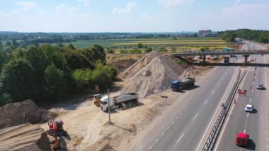 Taşlı ağır makineler. Yığınların yanında taşlarla taşınan yeni bir yol. Kamyonlar granit taşları yüklüyor. Hava görüntüsü.