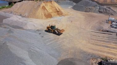 Modern endüstriyel bir fabrikanın havadan görünüşü. Asfalt bitkisinin geniş bölgesinde moloz ve kum yığınları. Buldozer kum taşır.