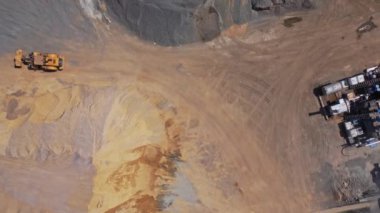 Taş ocağında buldozer. Endüstriyel makinenin hava görüntüsü kum yığınları ve ezilmiş taşlarla dolu büyük bir bölgede çalışıyor. Hareket kamerası..