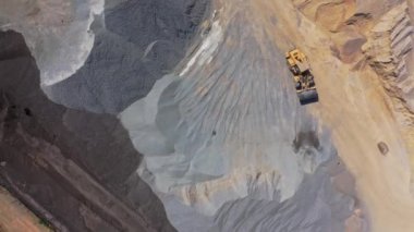 Buldozer büyük mezar yığınlarının arasında hareket ediyor. Yol inşaatı için kum ve harabelerle dolu devasa bir sanayi bölgesi. Hava Görünümü.
