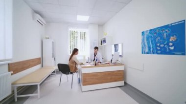 Genç bayan klinikte bir doktorla konuşuyor. Tıbbi dolapta oturup bir erkek uzmanla sohbet eden güzel bir kız. Sağlık hizmetleri kavramı.