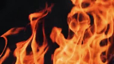Yanan ateş. Şenlik ateşi. Siyah arkaplanda yanan alevlerin yakınlaşması, yavaş çekim