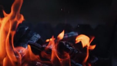 Yanan ateş. Şenlik ateşi. Siyah arkaplanda yanan alevlerin yakınlaşması, yavaş çekim