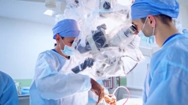 Mikroskopla operasyon. Bir hastaya ameliyat yapan bir grup cerrah. Doktorlar ameliyathanede modern ekipman kullanıyorlar..