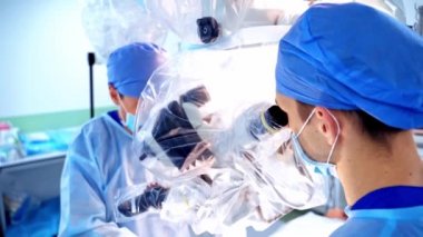 Doktorlar ameliyat sırasında mikroskoba bakarlar. Tıp çalışanları işletim sürecinde modern ekipmanları kullanırlar. Yakın plan..