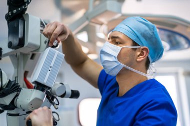 Ameliyathane için modern mikroskop. Ameliyat sırasında mikroskop kullanan bir grup cerrah.