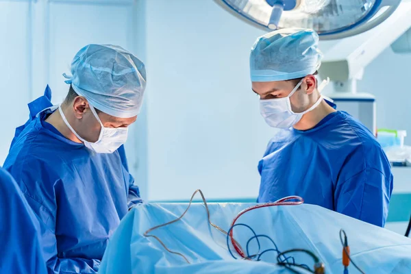 In surgery. Medical team performing operation in hospital operating theater. Working with surgical instruments.