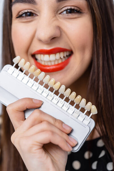 Check and select the color of the teeth in the dentist office. Process of choosing teeth color for a beautiful young girl.