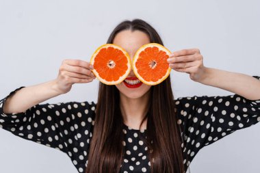 Gözlerinin yanında greyfurt yarımları tutan neşeli kız. Deli vejetaryen insan kavramı. Yüz ifadeleri.