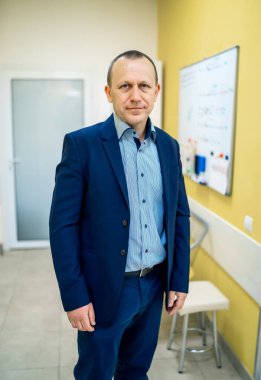 Klasik takım elbiseli yakışıklı adam kameraya bakıyor. Hastane koridorunun arka planı.