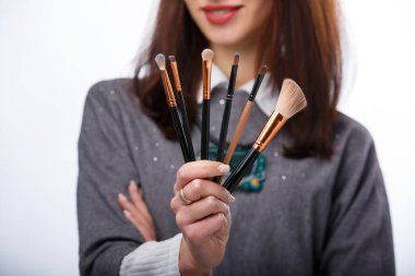 Makyaj fırçaları kadının elinde. Kozmetoloji konsepti. Kesilmiş fotoğraf.