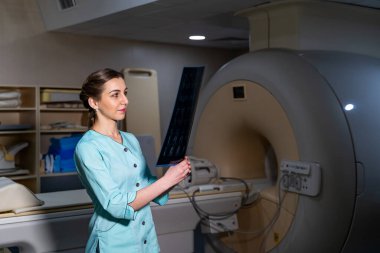 Doktor, manyetik rezonans görüntüleme makinesinin yakınındaki x-ray görüntüsünü açıklıyor..
