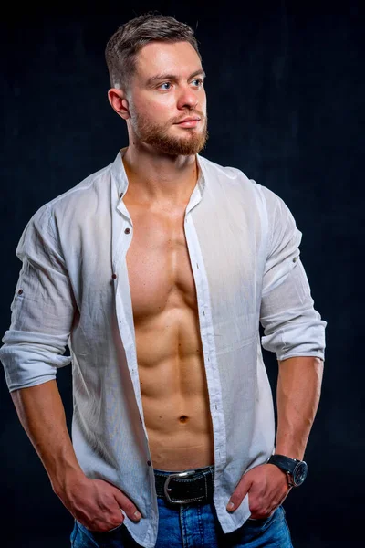 Super sexy man with tan abs and chest. Athletic man with unbuttoned white shirt on dark background. Studio portrait