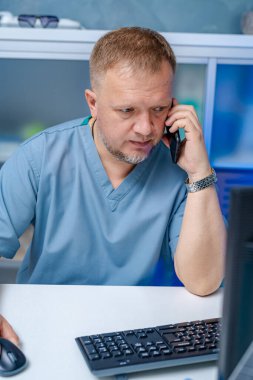 Tıp bürosundaki doktor. Tıp çalışanı bilgisayarın yanında telefonla konuşuyor. tıbbi konsept.