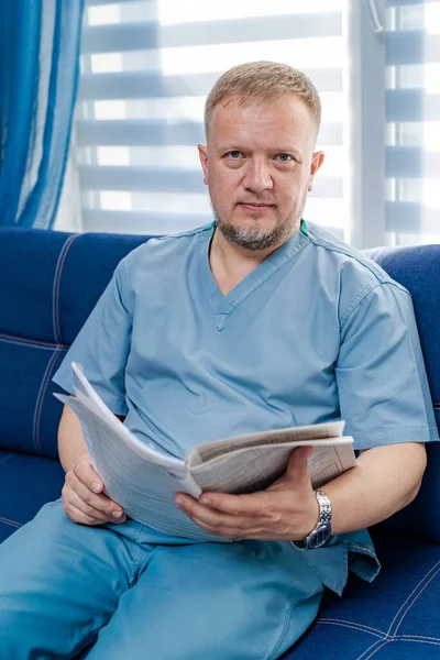 Portrait of a doctor or medical specialist. Vertical portrait. Man in scrubs. Papers in hands.