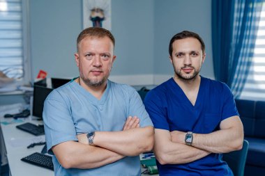 Önlüklü doktorlar ofiste el pençe divan duruyorlar. Tıp fakültesi geçmişi. Ciddi sağlık görevlileri.