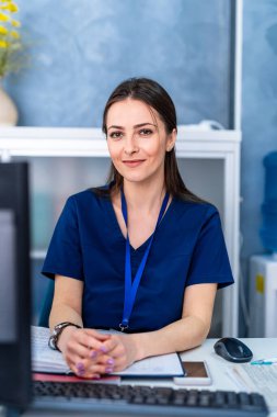 Genç ve yetenekli bir bayan doktor doktorun muayenehanesindeki kameraya bakıyor. Bilgisayar tomografi arkaplanı.