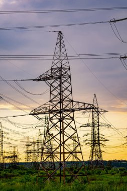 Yüksek voltaj direği. Yüksek voltajlı sütunlar günbatımına karşı. Enerji ve sanayileşme kavramı. Seçici odak
