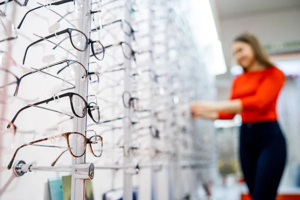眼鏡店 光学系の店内にメガネで立ってください 現代の眼科店で眼鏡をかけたショーケース 閉鎖だ 背景にぼやけた女 — ストック写真