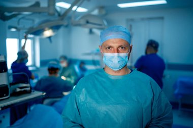 Profesyonel cerrahın portresi. Maske takan doktor. Profesyonel ekipmanların yanında tıbbî oturma.