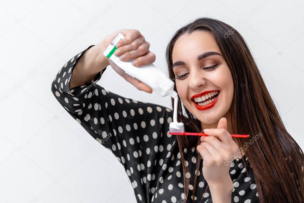 Young woman holding a toothbrush and placing toothpaste on it. Dental care concept.