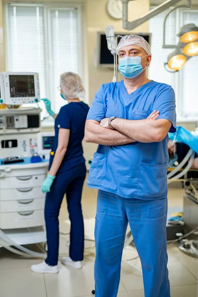 Doctor in blue medical clothes and mask is looking at camera. Medical chamber. First aid. Reanimation.