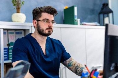 Ofisteki erkek doktor bilgisayarda çalışıyor. Modern hastane geçmişi.