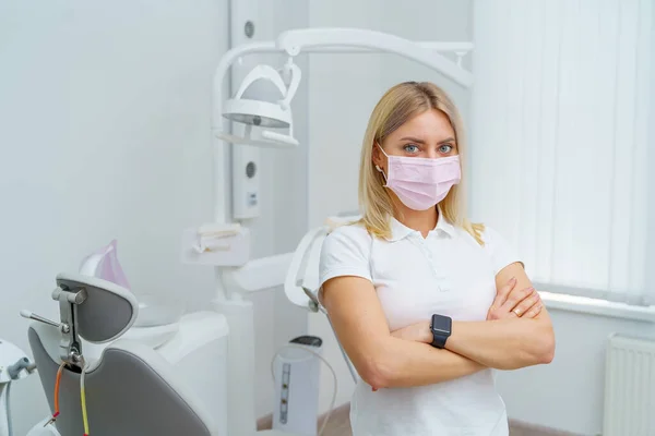 口腔衛生 歯医者の椅子の背景に立つ女性歯科医の肖像 — ストック写真