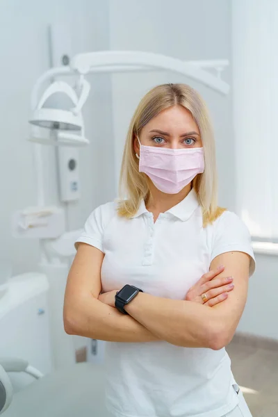 女性歯科医は医療マスクを身に着けているクロス手立っている 歯医者のキャビネットの背景 健康な歯の概念 — ストック写真