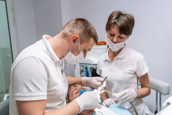 两名牙医检查病人的牙齿以进一步治疗 现代口腔科橱柜 — 图库照片