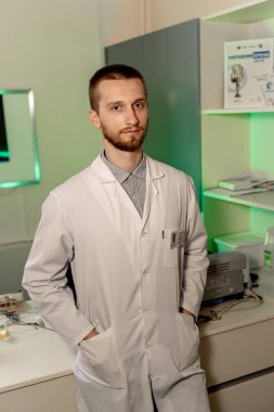 Masaya yaslanan ciddi bir doktor. Bilgisayar arkaplanı. Tıp bürosu. İşteki doktor. Teşhis.