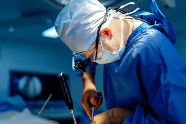 Omurga ameliyatı. Ameliyathanede ameliyat ekipmanlarıyla bir grup cerrah. Doktor ekrana bakıyor. Modern tıbbi geçmiş