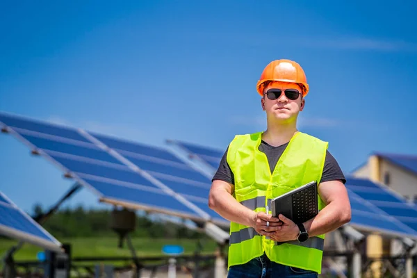 Engineer in sun glasses and helmet on a background of solar energy power station.