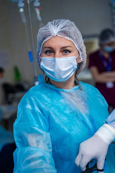 Doctor woman in blue medical clothes and mask is looking at camera. Medical chamber. First aid. Reanimation.