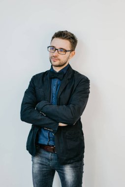 Kot pantolonlu genç adam. Ceket ve gömlek giyiyor. Boe kravatı takın. Çapraz yumruklar.