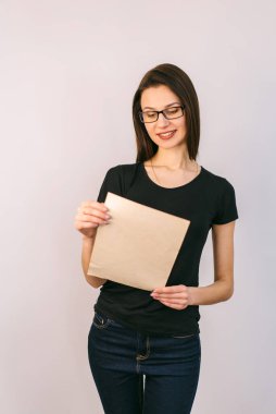 Pretty girl in glasses holds document in hands. Paper shit in hands. White background.