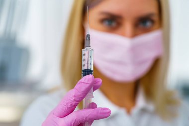 Doktor ya da hemşire ellerinde bebek ya da yetişkin aşısı olan pembe eldivenler tutuyorlar. İlaç ve uyuşturucu kavramı.