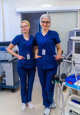 Kadın doktor portresi mi? Hastanede. Kameraya bakıp gülümsüyor. Modern ekipman arkaplanı.