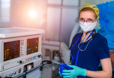 Ciğerlerin oksijenle havalandırılması. COVID-19 ve koronavirüs teşhisi. Yüz maskeli ve eldivenli doktor akciğer entübatonu için maske ayarlar. Zatürree teşhisi. Salgın.