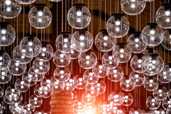 Vintage light. Bulb lamp hanging from celling in the house. Many lumps, glass transparent round lamps.